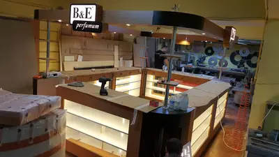 B&E Perfumum — AVM kiosku — koyu ceviz tonlu laminat, raf altı LED şerit