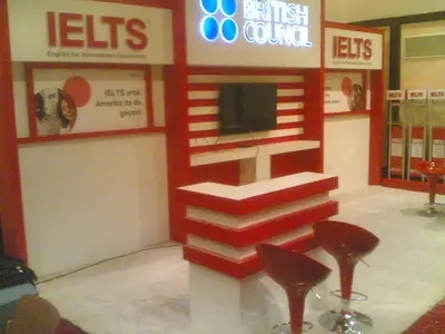 British Council IELTS — stand de feria — asientos tapizados, pantalla plana montada (la unidad ya instalada)