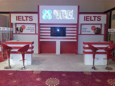 British Council IELTS — stand de feria — asientos tapizados, rojo (la unidad ya instalada)