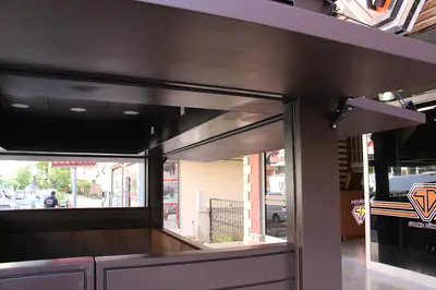 Emaar Square — Straßenkiosk — Metall-Rollladen, Holzton (im Straßenraum)