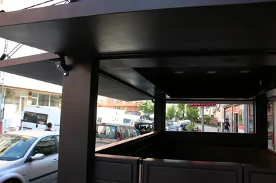 Emaar Square — Straßenkiosk — perforierte Metallverkleidung, Holzton (im Straßenraum)