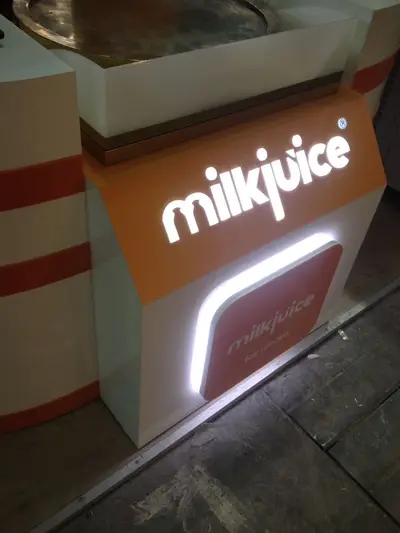 Milk Juice — fuar standı — süpürgen kanat formlu kanopi, monte düz ekran (sahada montaj)