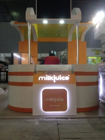 Milk Juice — fuar standı — süpürgen kanat formlu kanopi, monte düz ekran (yerine kurulmuş hâli)