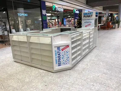 Smartpunkt — mall kiosk — white laminate panels, under-shelf LED strip